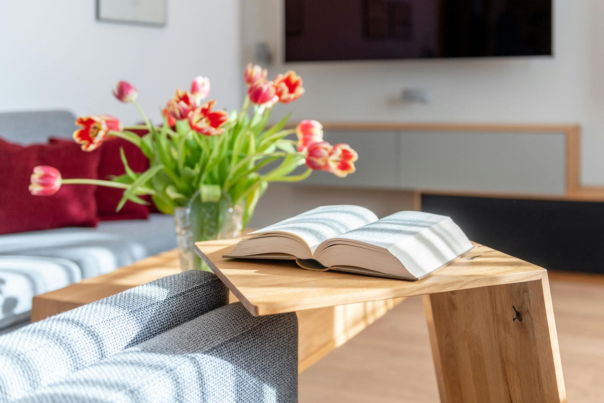 Generalsaniertes Wohnzimmer eines Einfamilienhauses mit hellem Interior-Design und gemütlicher Sitzecke mit grauem Sofa.